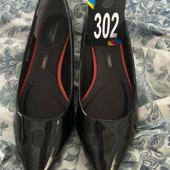 M302 Rockport total motion Women’s flats of black patten. Has cushioned insole.