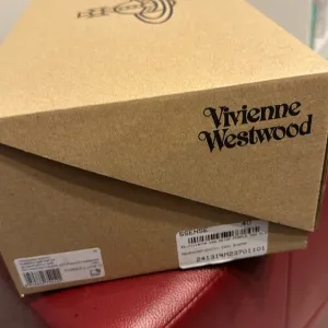 Vivienne Westwood designer sneakers are size 7. Beige with a purple design.